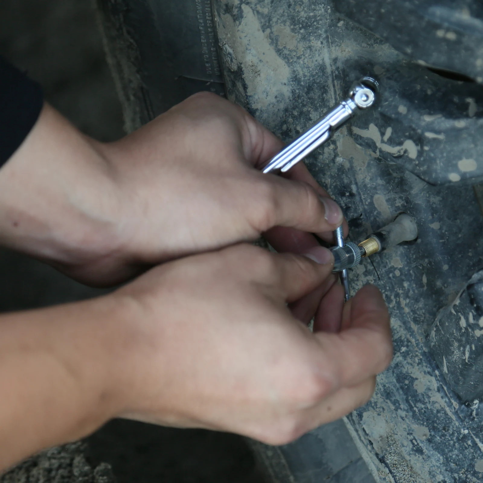 Checking tire pressure with a pencil gauge pressed onto the valve stem