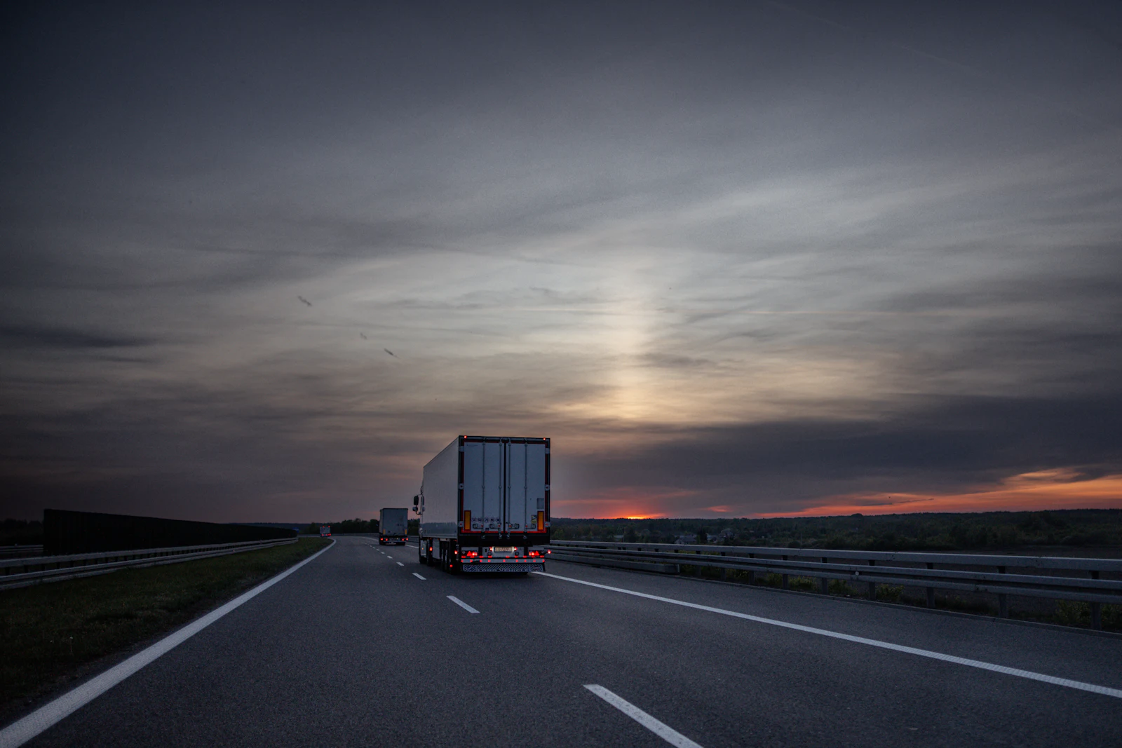 Semi-trailer truck on an open highway at dusk