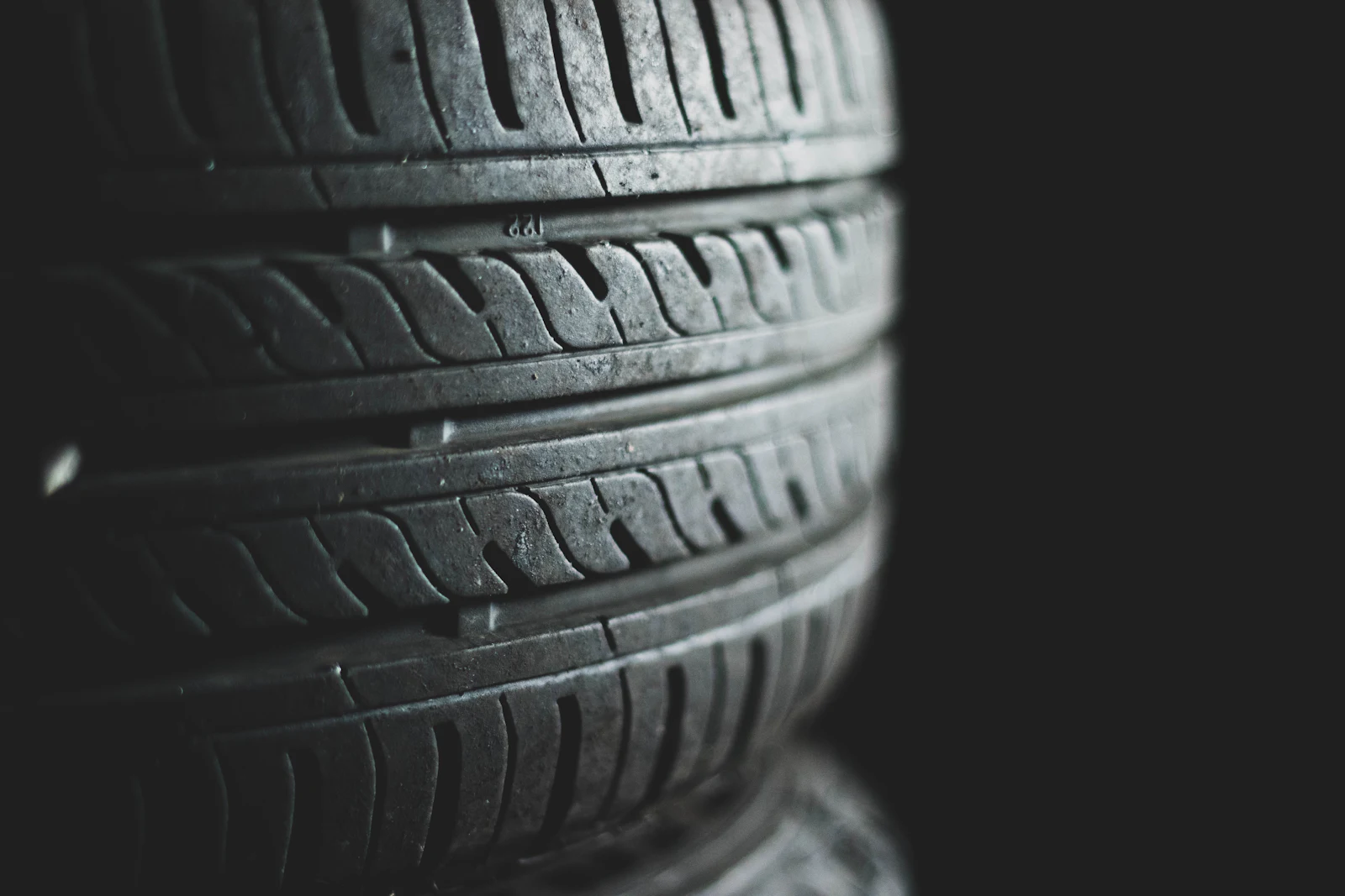 Stacked passenger tires in low light, tread facing out