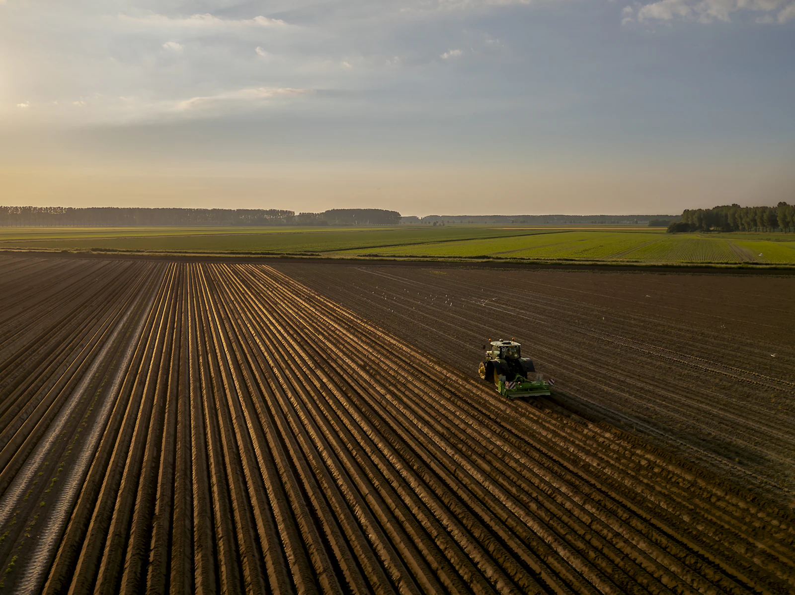 Tractor working a freshly plowed field at sunset