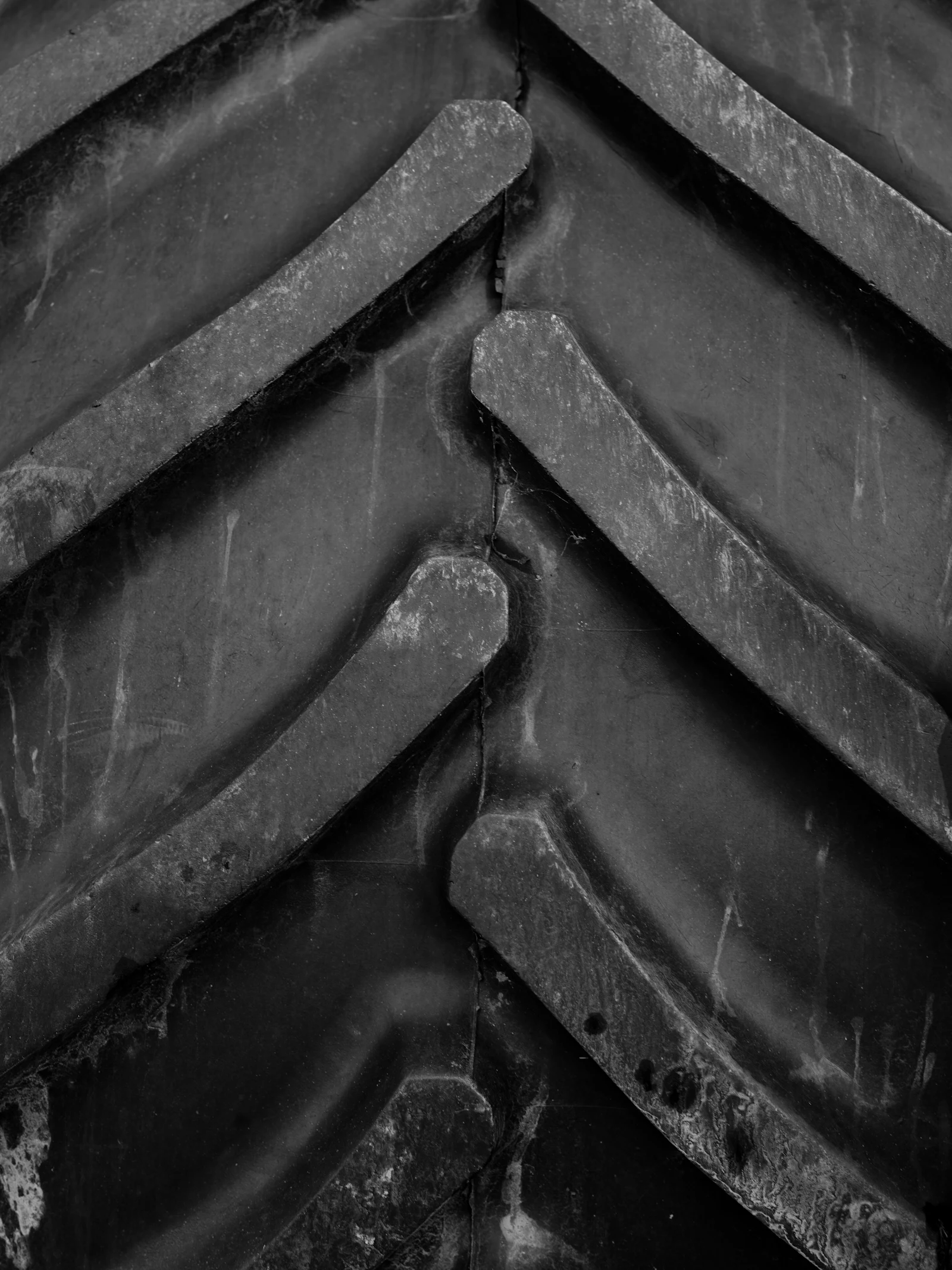 Black-and-white close-up of the angled lugs on a tractor tire