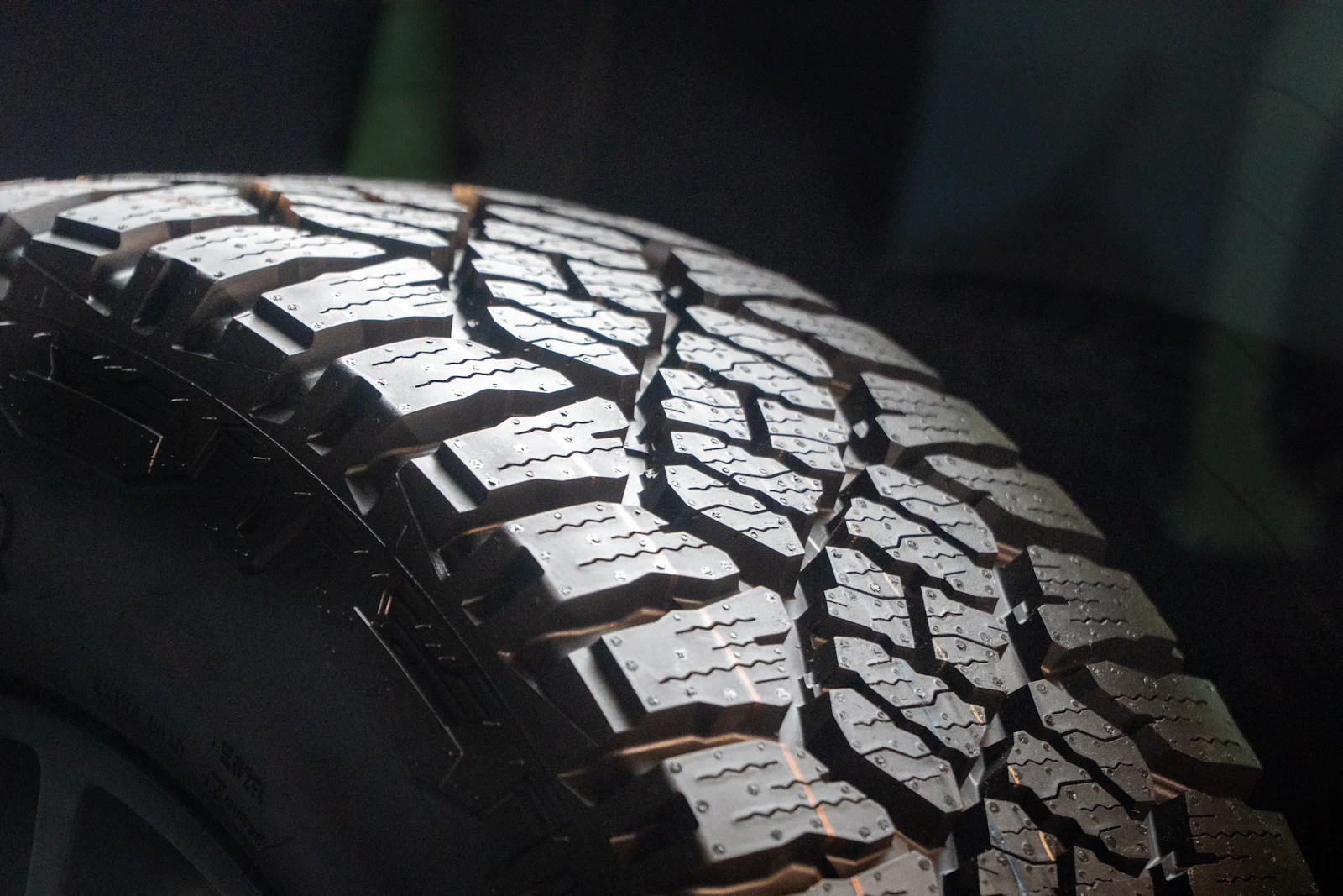All-terrain tread blocks on a light truck tire against a dark background