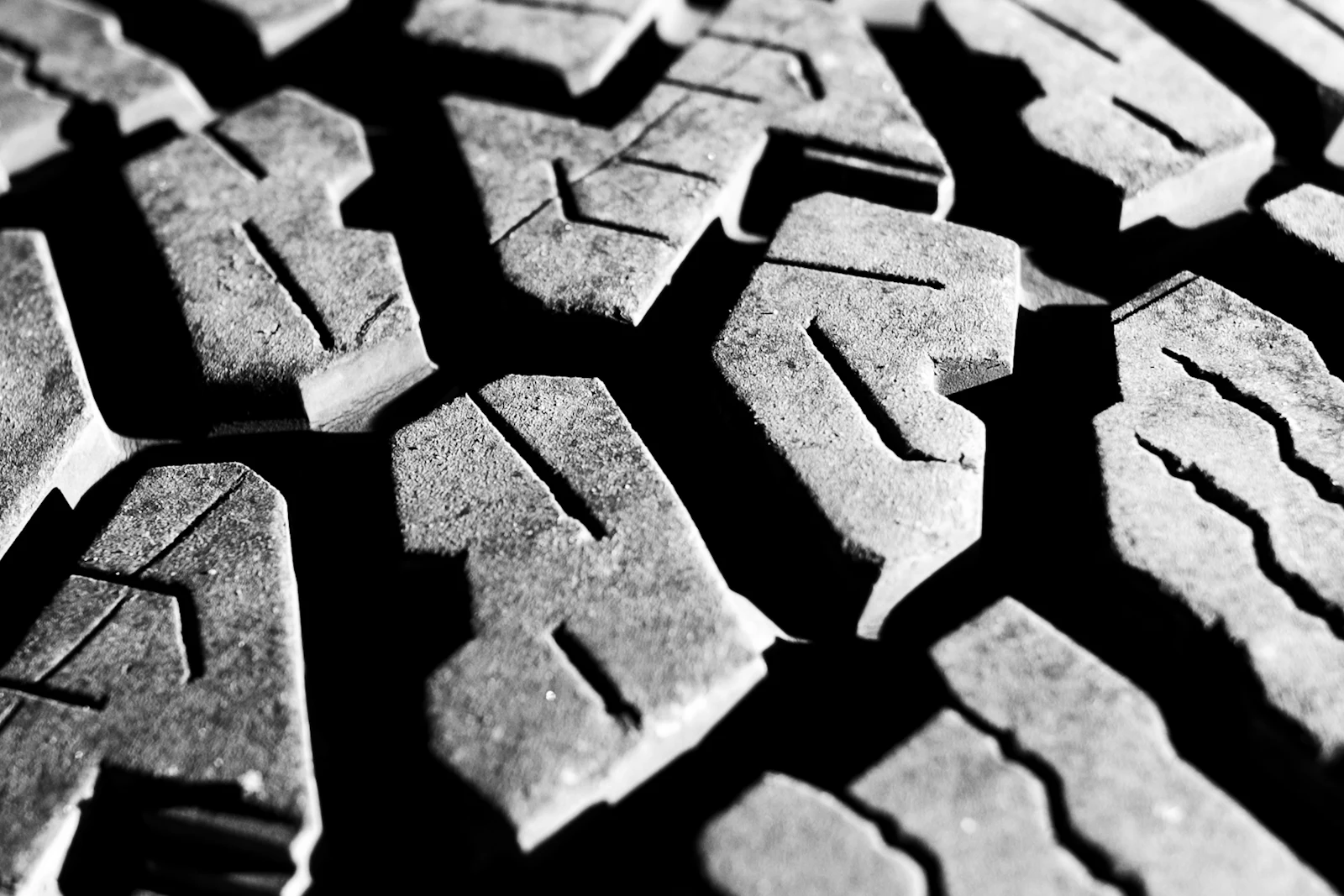 Black-and-white close-up of chunky off-road tread blocks with sipes