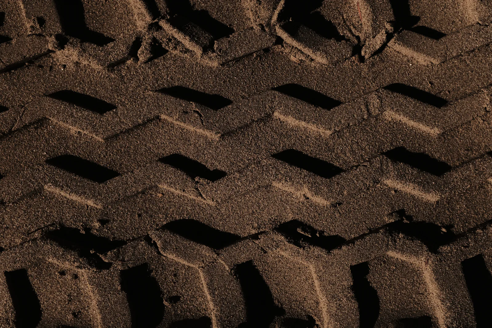 Tread pattern pressed into sand, the footprint a tire leaves where it meets the ground